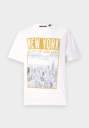 T-shirt en coton blanc avec un grand graphique de la skyline de New York en niveaux de gris, avec l'inscription dorée "NEW YORK CITY OF DREAMS" au-dessus.