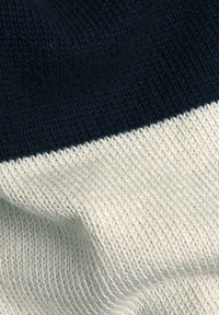 Tessuto a maglia con una parte superiore blu navy e una parte inferiore crema, che presenta un motivo di tessitura a trama.
