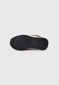 La suela del zapato presenta un material de goma texturizada negra con un patrón de banda de rodadura multidireccional y un acento de entresuela blanca.