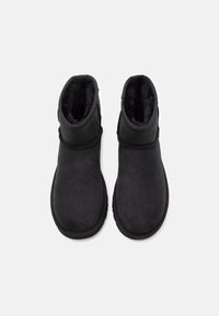 Černé semišové kotníkové boty s měkkou, hebkou vnitřní podšívkou. Kulatá špička a výška kotníku, s prošívaným švem a bez viditelného kovového hardwaru.