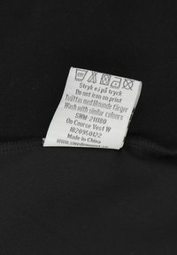 Vaskeanvisning med vaske-symboler og instruktioner på engelsk og svensk, der siger "Stryg ikke på tryk" og "Vask med lignende farver."