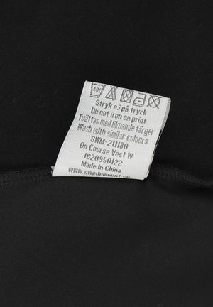 Zwarte stof met een waslabel dat wasinstructies en materiaaldetails toont, met grijze tekst en verzorgingssymbolen op een witte achtergrond.