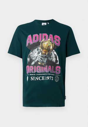 Tumši zaļš kokvilnas T-krekls ar lielu grafisku attēlu ar zelta trofeju, ar tekstu "ADIDAS ORIGINALS" rozā krāsā un "SINCE 1972" apakšpusē.