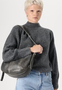 Gray ribbed sweater with a high collar, paired with a dark gray leather shoulder bag featuring a curved silhouette and silver hardware.