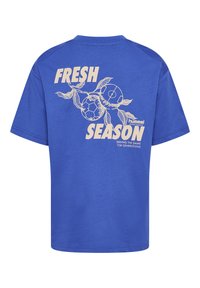 Blauwe katoenen t-shirt met een grafisch ontwerp met de tekst "FRESH SEASON" en voetballen met bladeren op de achterkant. Korte mouwen, ronde hals.