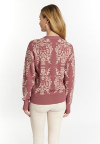 Maglione rosa con un motivo floreale e di uccelli crema, maniche lunghe, polsini e orlo a coste, realizzato in morbido tessuto a maglia.
