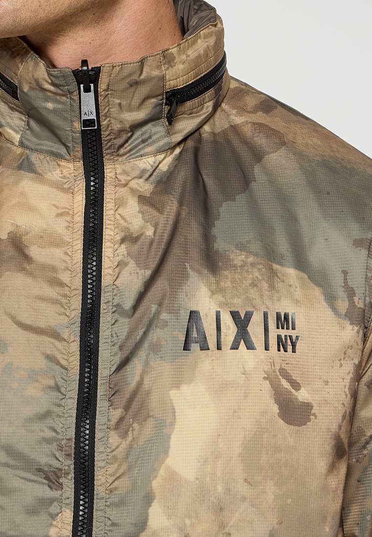 Camouflagejas met een hoge kraag, ritssluiting en zwart logo "AIX|MINY" op de linkerkant van de borst, gemaakt van lichtgewicht, gestructureerd materiaal.