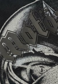 Čierne bavlnené tričko s textúrovaným sivým a čiernym grafickým dizajnom tváre, s výrazným, vyvýšeným nápisom "Motor".