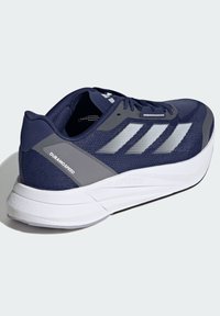 Scarpa da corsa navy con parte superiore in rete, accenti grigi, tre strisce riflettenti e suola bianca ammortizzata. Caratterizzata dal marchio "DURAMOSPEED".