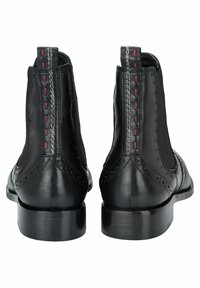 Stivali Chelsea in pelle nera con lati elastici, dettagli brogue, cuciture rosse e grigie sul retro e un tacco leggero. Texture liscia.