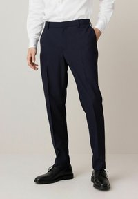 Navy-blau gestreifte Anzughose mit slim fit, ausgestattet mit Gürtelschlaufen, Fronttaschen und einer glatten Textur, kombiniert mit schwarzen Dressschuhen.