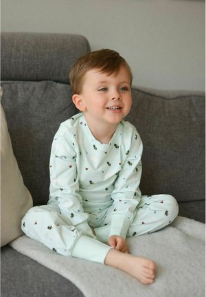Mente vihreä pyjama-asuste, jossa on mehiläisen ja kukan kuosi, valmistettu pehmeästä kankaasta. Pitkät hihat ja kapeat housut ribbauslahkeilla.