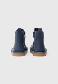 Ναυτικές δερμάτινες μπότες ankle με λείο φινίρισμα, πλαϊνούς φερμουάρ και αντίθετη καφέ καουτσούκ σόλα. Διαθέτουν ενίσχυση στο τακούνι.