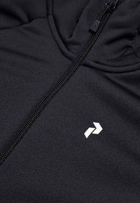 Nahaufname einer schwarzen Kapuzenjacke mit einem weißen, kantigen Logo auf der Brust und einem schwarzen Zipper-Zug.