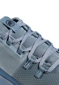 Tige de chaussure de sport en différentes nuances de bleu, fabriquée à partir de maille texturée et de matière synthétique, avec des lacets plats et un patch logo.