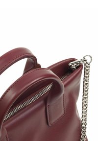 Borsa a mano in pelle bordeaux con doppi manici, una cerniera argentata e una tracolla a catena removibile. Texture liscia con design minimalista.