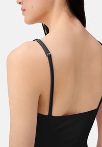 Indumento nero senza maniche con sottili spalline regolabili, caratterizzato da una texture liscia e un design aderente, con spalle e schiena visibili.