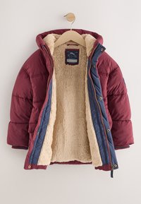 Veste matelassée bordeaux avec accents bleu marine, dotée d'une doublure en fausse fourrure crème douce. Fermeture éclair à l'avant, capuche et détails en métal doré.