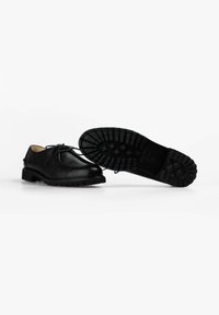 Zapatos de cuero negro con cordones, con un upper texturizado y suela de goma gruesa que presenta un patrón de tracción robusto. Acabado suave con puntera redonda.