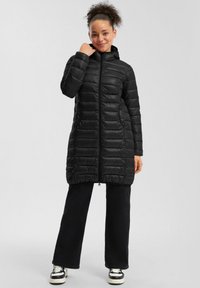 Must musta jope, millel on kapuuts, ees lukk, horisontaalne tikand ja küljetaskud. Kombineeritud mustade pükstega ja tossudega.