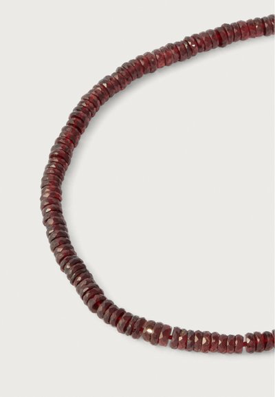 Piros drágakő nyaklánc, kerek, csiszolt gyöngyökkel, sima textúrával és gazdag színnel, folyamatos kör alakú elrendezésben.