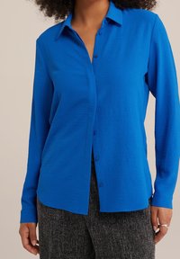 Blaues Langarm-Hemd mit Knöpfen aus leichtem Stoff. Verfügt über einen Kragen und einen lockeren Schnitt, mit strukturiertem Muster und sanftem Glanz.