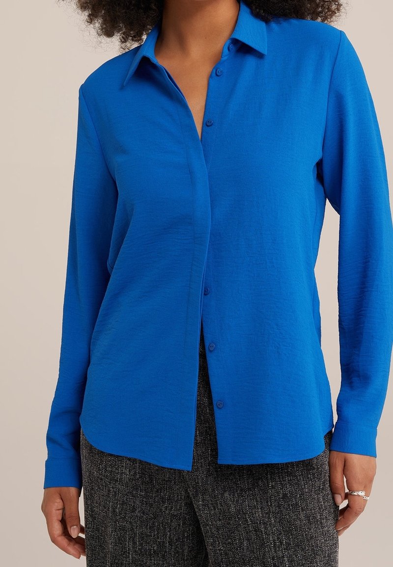 Blaues Langarm-Hemd mit Knöpfen aus leichtem Stoff. Verfügt über einen Kragen und einen lockeren Schnitt, mit strukturiertem Muster und sanftem Glanz.