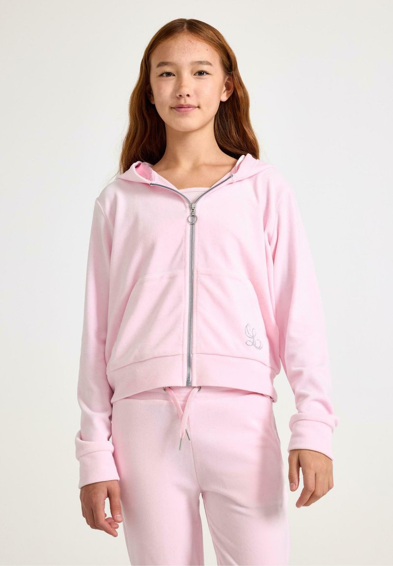 Różowa bluza z kapturem na zamek, uszyta z miękkiego materiału, z kieszeniami z przodu i elastycznymi mankietami. Połączona z dopasowanymi różowymi dresami z troczkami.