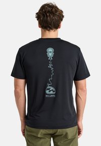 Camiseta negra de manga corta con un diseño gráfico turquesa de caras abstractas y un globo en la parte posterior, fabricada con un material transpirable.