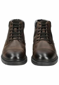 Botas de tobillo de cuero marrón con un acabado suave, acentos negros, diseño con cordones y suelas de goma. Presenta detalles de costura en los laterales.