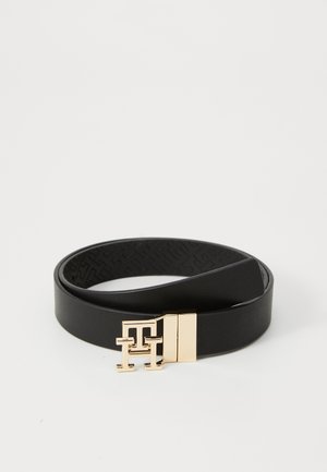Zwarte leren riem met een goudkleurige gesp met een logo ontwerp. De riem heeft een gladde textuur en een reliëfpatroon aan de binnenkant.