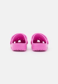 Pink rubber clogs with open back, textured inner lining, and ventilation holes. Non-slip sole with raised patterns for traction.