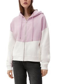 Felpa con zip di colore rosa pastello nella parte superiore e bianca nella parte inferiore, realizzata in tessuto morbido con una vestibilità rilassata e cordini regolabili.