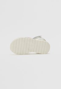 Weiße Sneakers mit einer strukturierten Gummisohle, die mehrfarbige Akzente in Pink und Grau auf einem glatten Obermaterial aufweisen.
