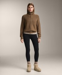 Rjav rebrast pleten sveter z visokim ovratnikom, prelit preko svetle majice, v kombinaciji s črnimi legginskami in svetlo rjavimi gležnjarji s krznom.