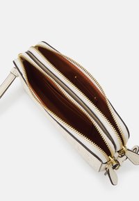 Jasnokremowy portfel ze skóry z złotymi zamkami błyskawicznymi, dwoma głównymi przegrodami oraz brązową podszewką wewnętrzną. Posiada kieszenie na karty i dekoracyjny akcent.