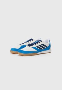 Zapatos deportivos de cuero y sintético con una combinación de colores blanco, azul y marino; diseño de corte bajo con suela de goma y acentos de tres franjas.