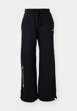 Pantalons de survêtement noirs en coton, dotés d'une taille élastique avec cordon de serrage, de fentes sur les côtés au niveau de l'ourlet et d'un texte contrastant orange et blanc sur une jambe.