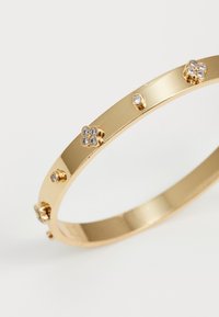 Guldbangle armbånd med en glat finish, udsmykket med blomster- og cirkulære detaljer, der er indlagt med små ædelsten.