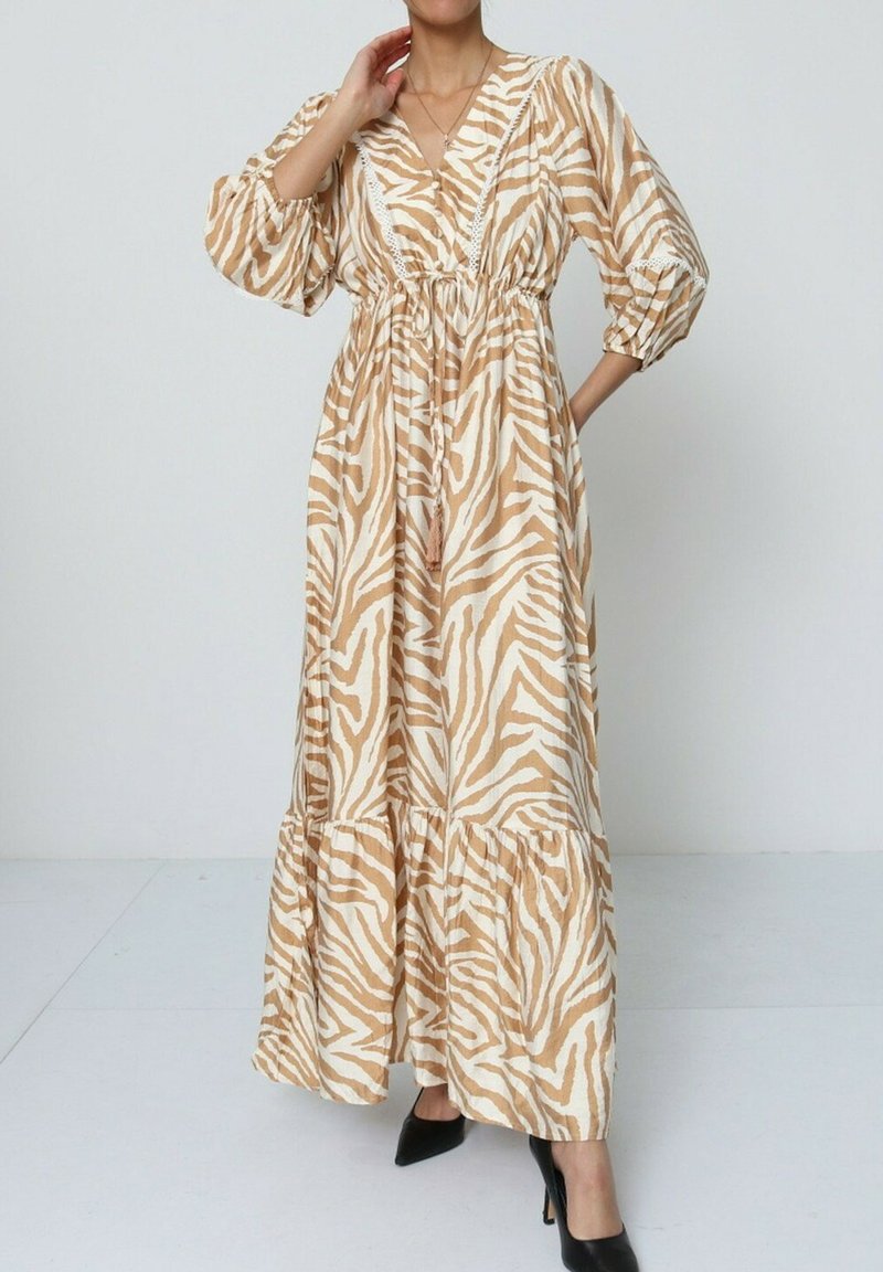 Robe longue à manches bouffantes avec un imprimé zèbre beige et blanc, dotée d'un décolleté en V et d'une taille froncée, avec un ourlet à volants et un accent à frange.