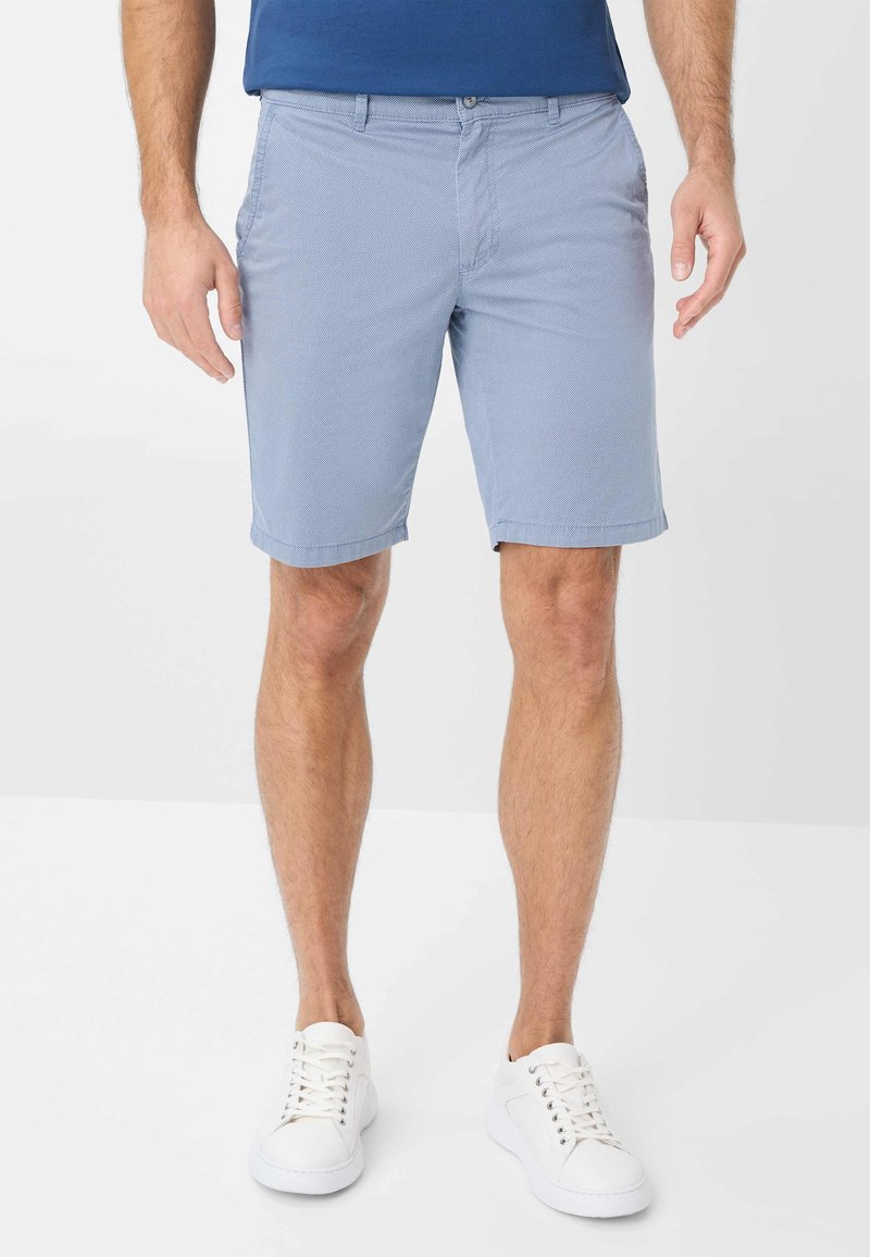 Helle blaue Shorts aus strukturiertem Stoff, mit geradem Schnitt, aufgerollten Säumen und Seitentaschen, kombiniert mit weißen Sneakers.