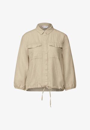 Beige skjorte med lange ærmer, knaplukning og krave, to brystlommer, elastiske manchetter og en snor i hæmmen for justerbar pasform.