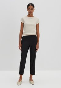 Cream ribbed short-sleeve top, black tailored trousers, and light-colored flat shoes. Simple design with a fitted silhouette and a smooth texture.