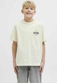 Camiseta de algodón de color amarillo claro con cuello redondo y mangas cortas, que presenta un gráfico frontal con el texto "EDITION" en letras oscuras.