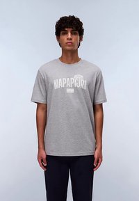 Grå bomulds T-shirt med korte ærmer, med et hvidt trykt logo "NAPAPIJRI" tværs over brystet. Ensfarvet design, almindelig pasform.