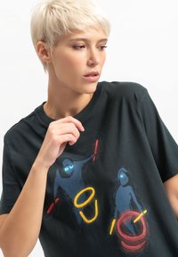 T-shirt nera in cotone con figure astratte disegnate in blu, rosso e giallo. Maniche corte e scollo rotondo.