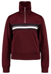 Burgundský pulovr s vysokým límcem a polo zipem, s černo-bílým horizontálním pruhem přes hruď. Hladká, elastická tkanina.