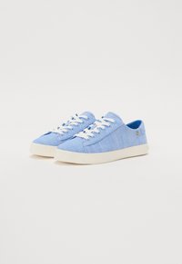 Sneakers low-top azzurro chiaro con lacci bianchi e suole in gomma, dotati di un piccolo logo dorato sul lato, su sfondo bianco.