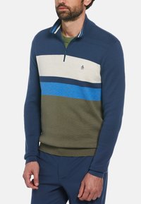 Pull à col zippé navy avec un design rayé en crème, bleu foncé, bleu clair et vert olive. Il présente un logo sur la poitrine et des poignets côtelés.