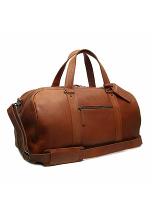 Sac de voyage en cuir marron avec double poignée, poche avant zippée, bandoulière réglable et une étiquette bagage sur fond blanc.